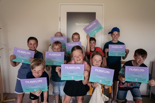 Kinderen houden trots hun eigen filmdiploma omhoog na een pop-up workshop